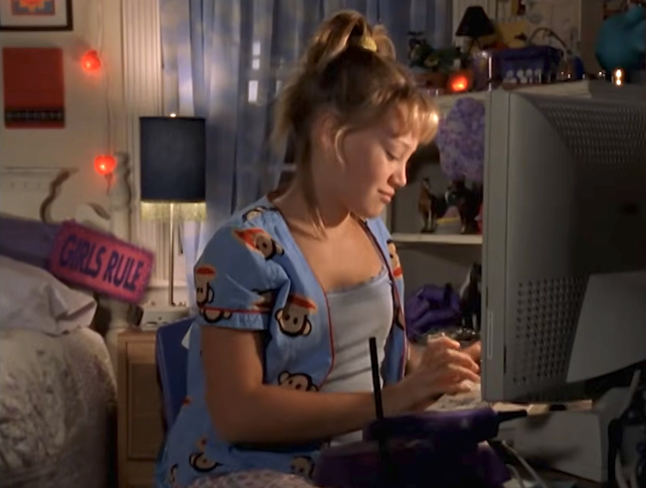 Hilary Duff typing at a computer with a smirk on her face