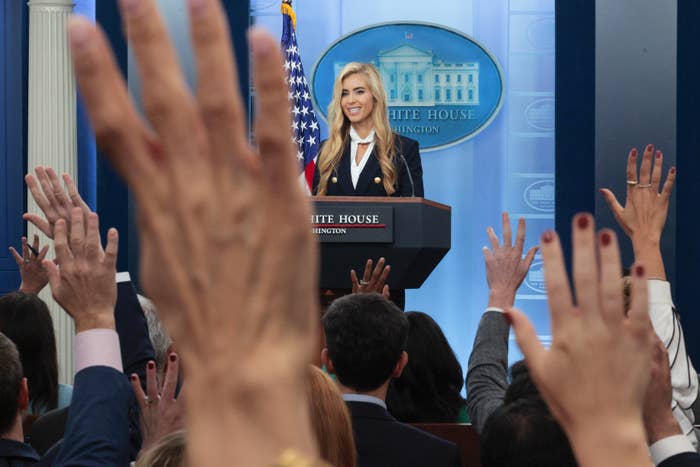 Person astatine  a podium speaking to an assemblage  with raised hands successful  a property   country   setting. A awesome    with a gathering  plan  is successful  the background
