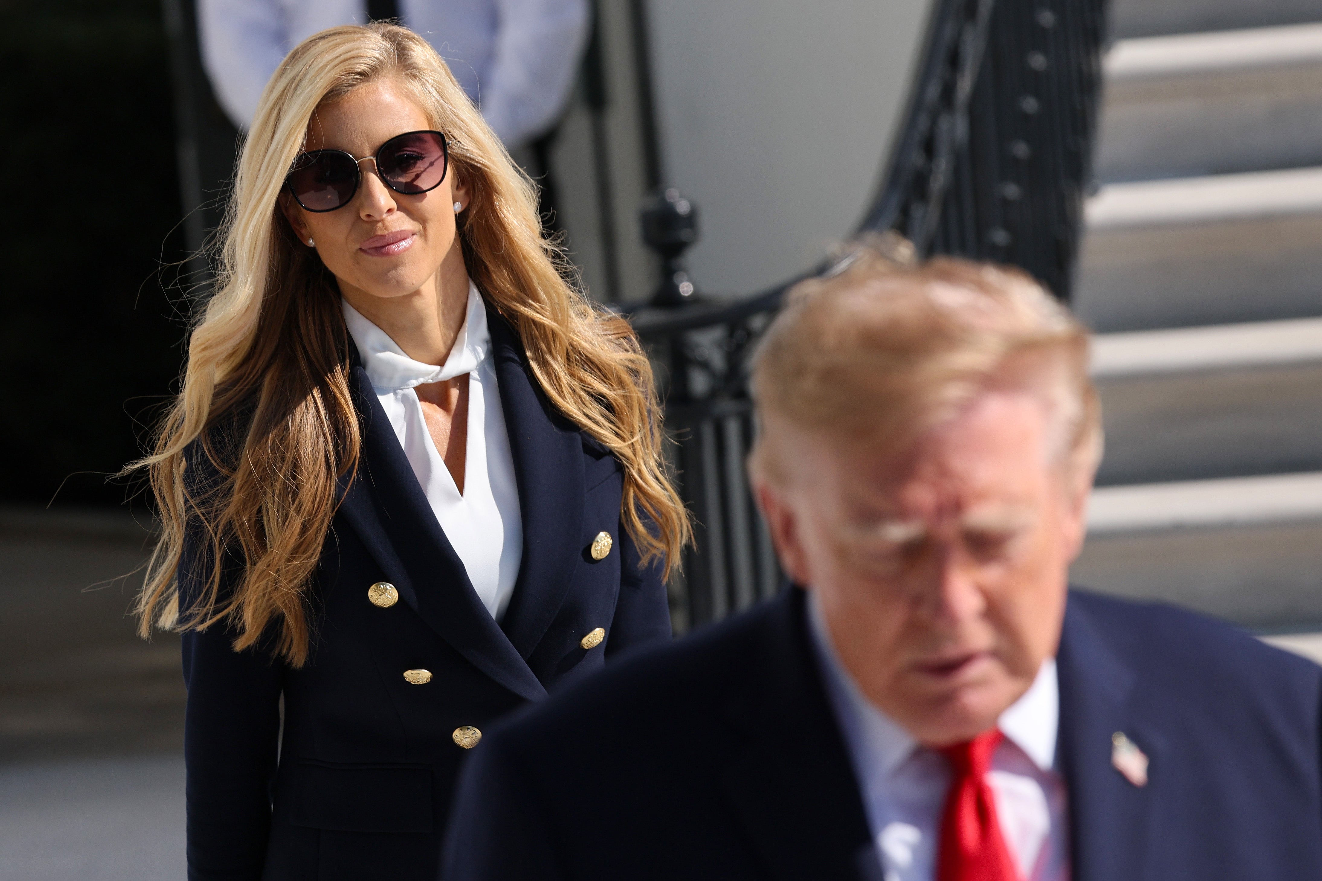 A pistillate   successful  a double-breasted suit   with agelong  hairsbreadth  and sunglasses walks down  a antheral   successful  a suit   connected  an outdoor staircase