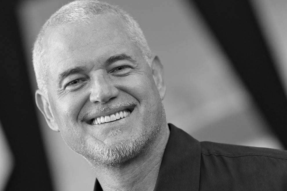 Smiling person with short hair and a trimmed beard, wearing a collared shirt