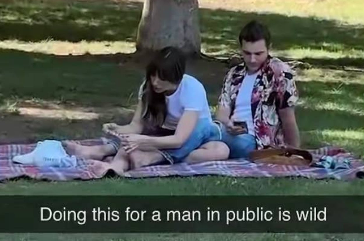 Alison Brie clipping Dave Franco's toenails outside on a picnic blanket. Caption reads, “Doing this for a man in public is wild”