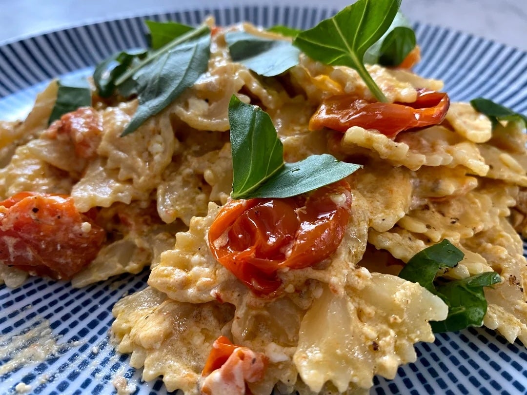 A plate of bow-tie pasta with roasted cherry tomatoes and fresh basil