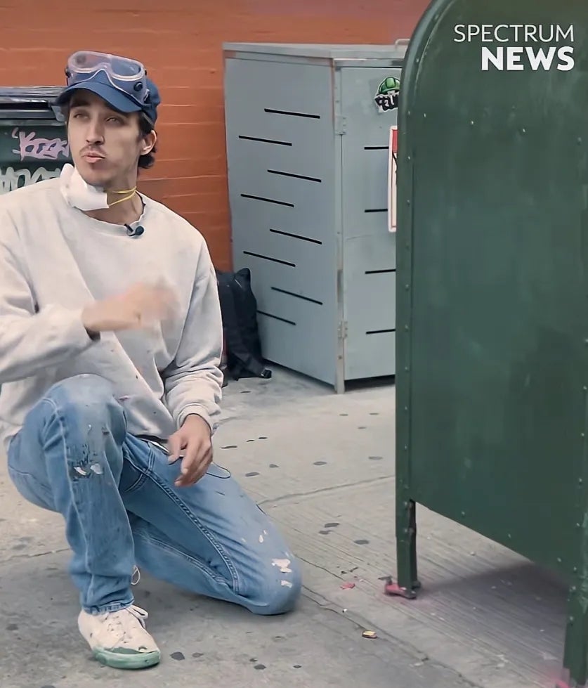 SweetP kneeling on sidewalk, gesturing; he is wearing jeans, gray sweatshirt, and goggles. Text reads: "Rusting Out." Nearby are paint supplies and a metal mail