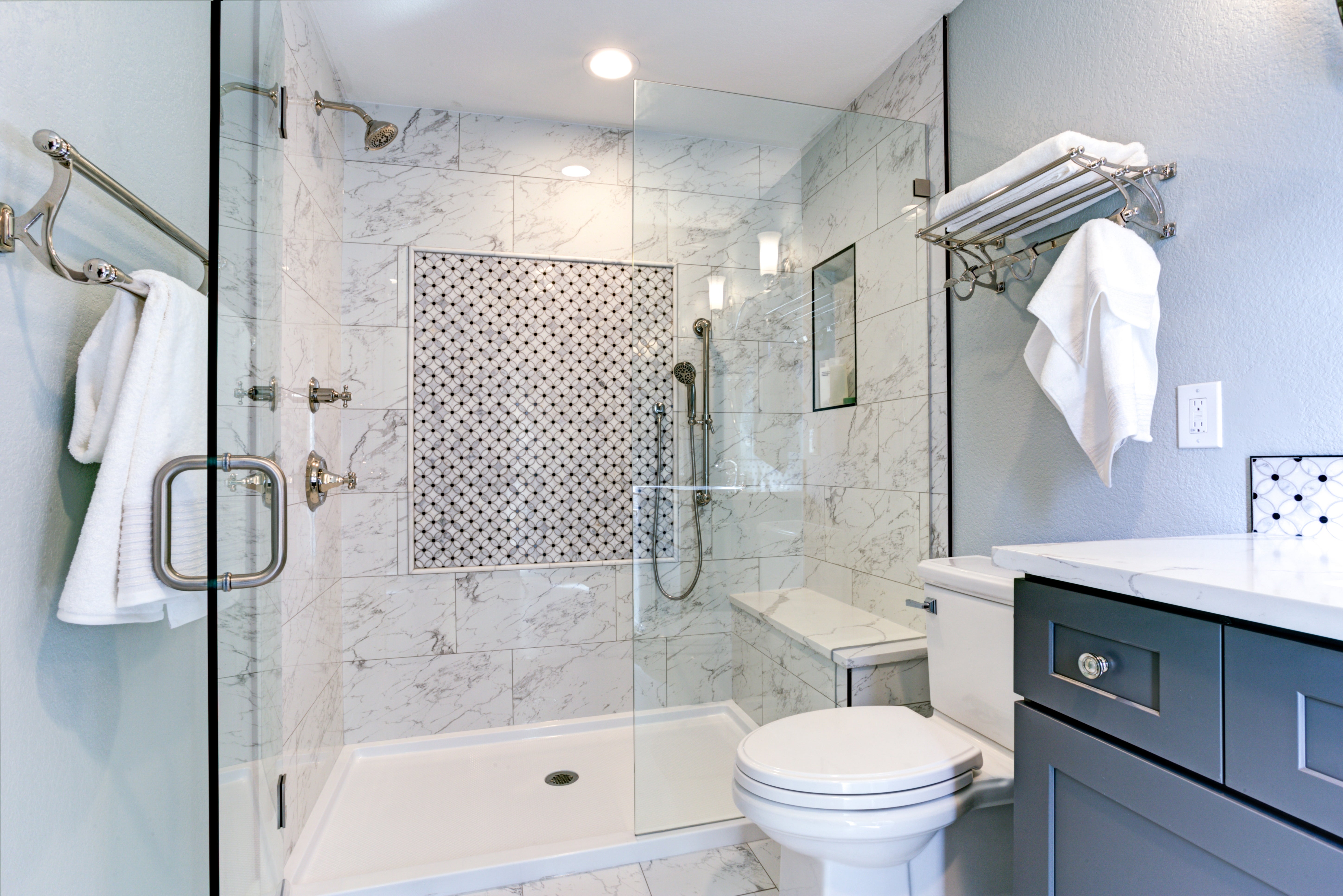 Elegant modern bathroom with glass-enclosed shower, marble tiles, and a sleek vanity