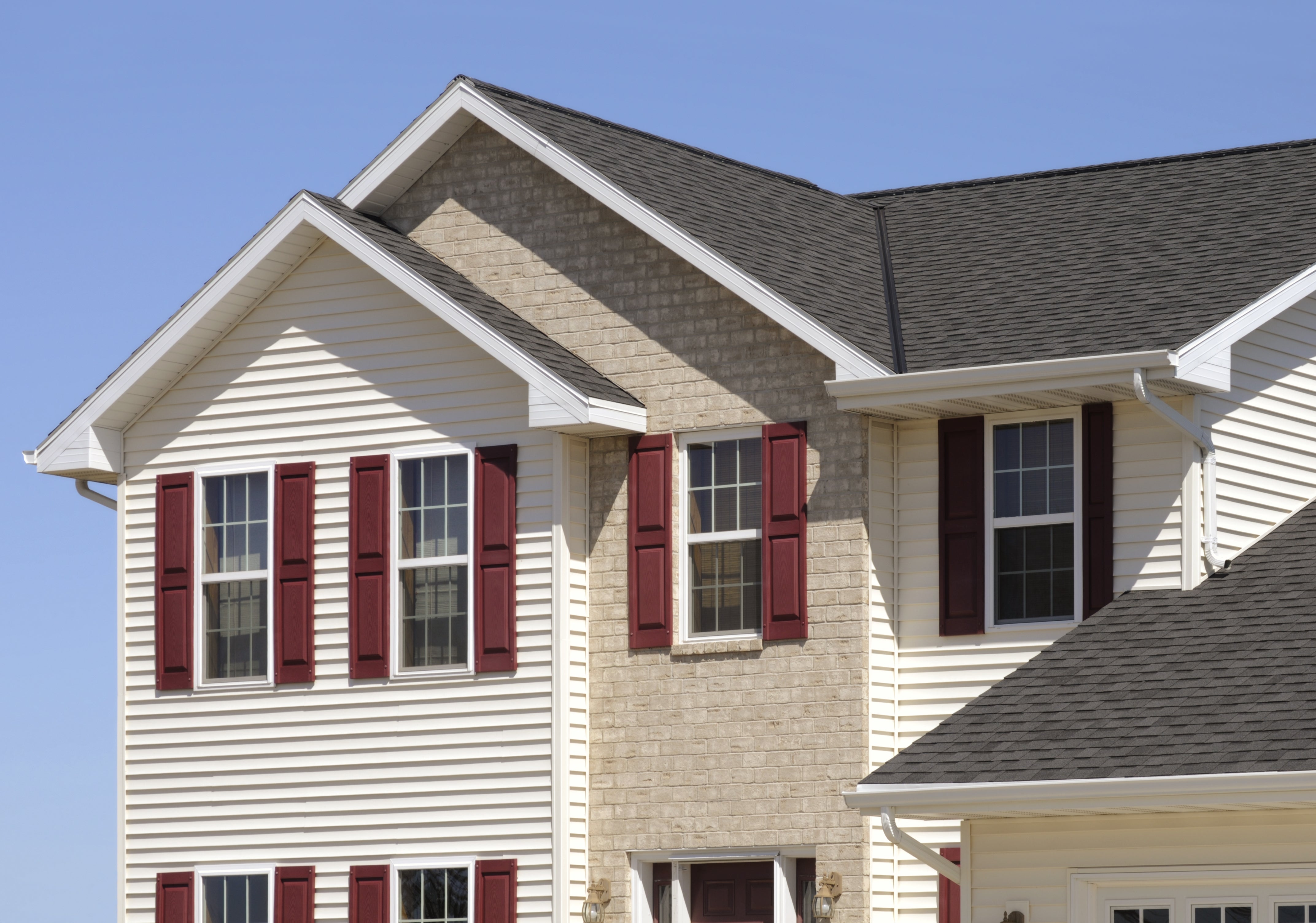 The image shows a suburban two-story house with brick and siding exterior, featuring multiple windows and prominent red shutters