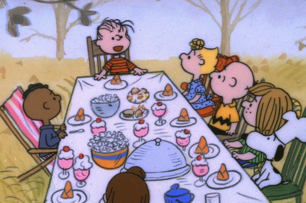 Cartoon characters gathered around a table with a feast, enjoying various dishes and desserts