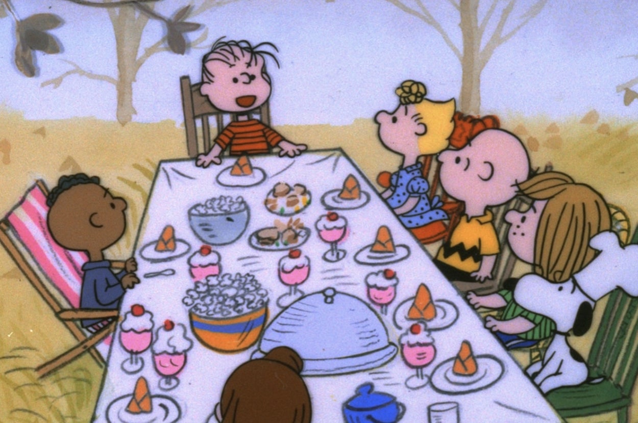 Cartoon characters gathered around a table with a feast, enjoying various dishes and desserts