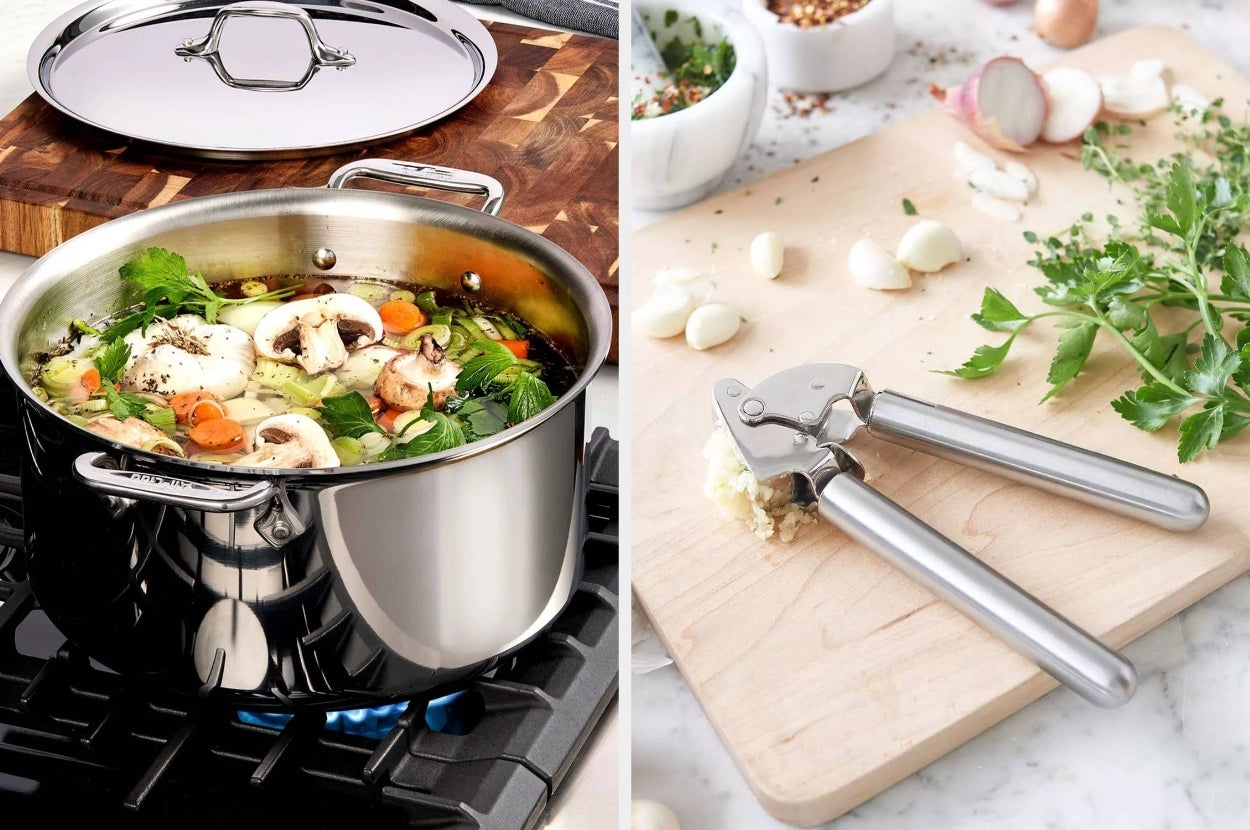 A stainless steel pot with soup on a stove next to a cutting board with garlic, herbs, and a garlic press, suggesting kitchen shopping