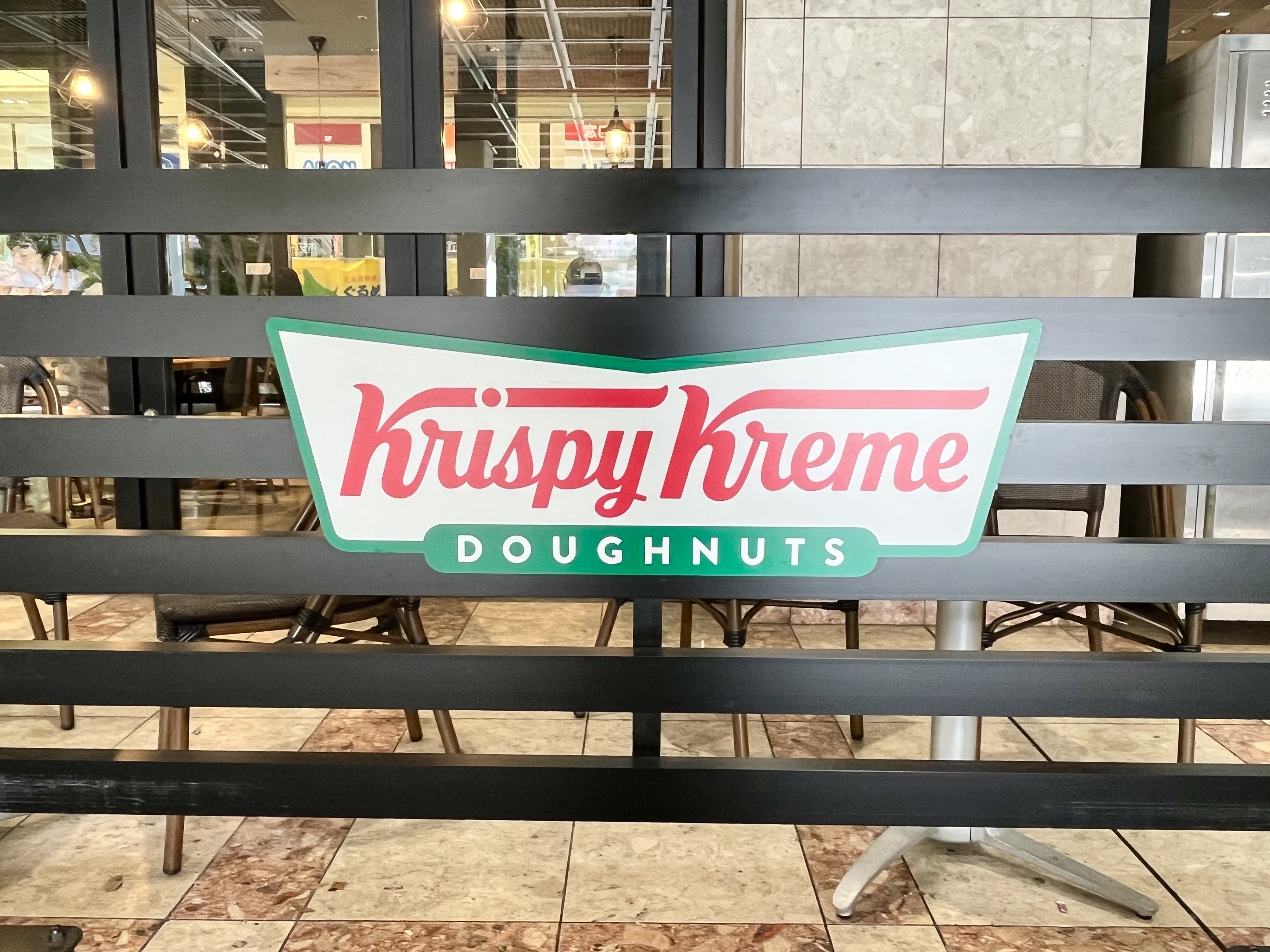 クリスピー・クリーム・ドーナツの看板がカフェの柵に取り付けられています。