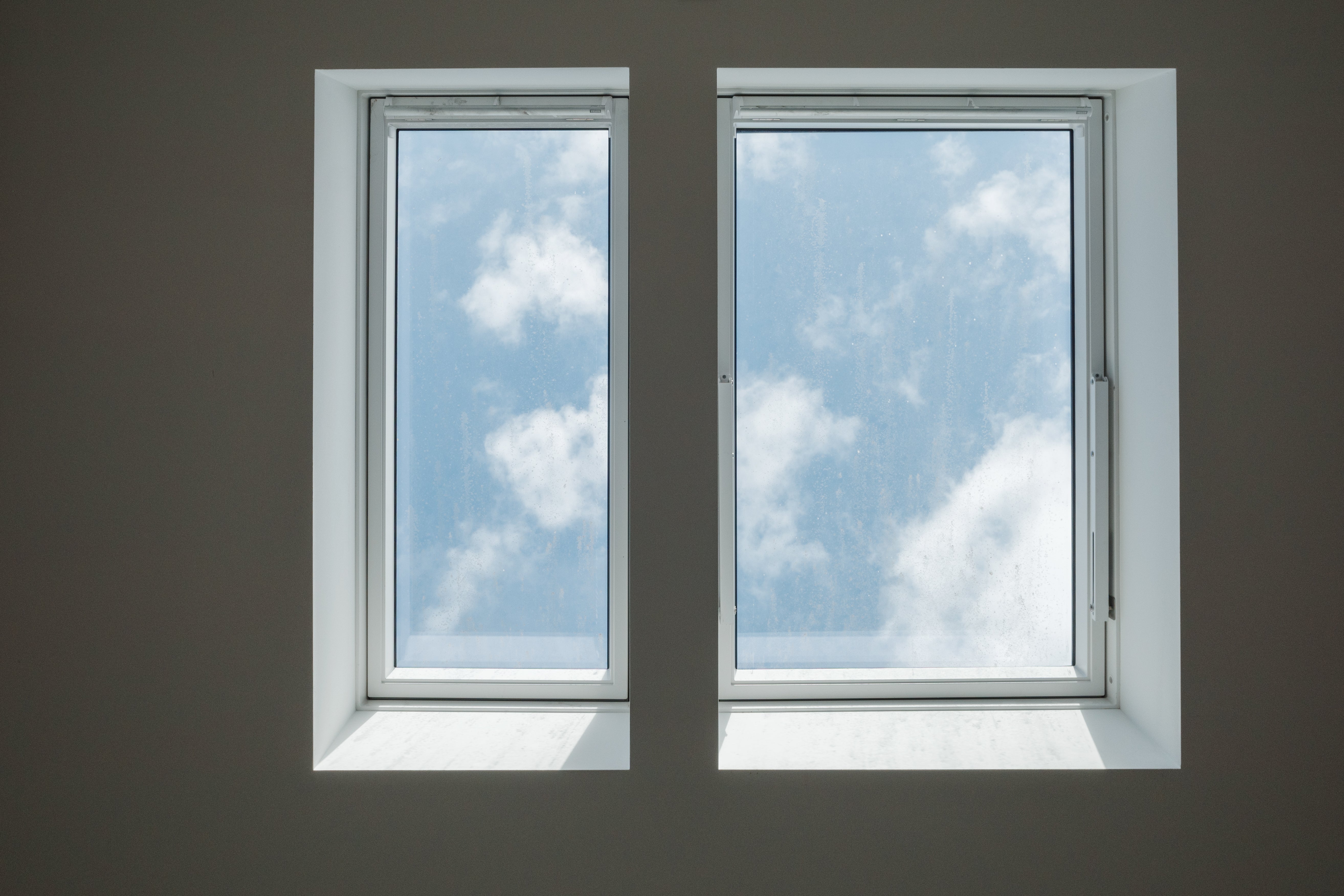 Two rectangular windows showing a partly cloudy sky