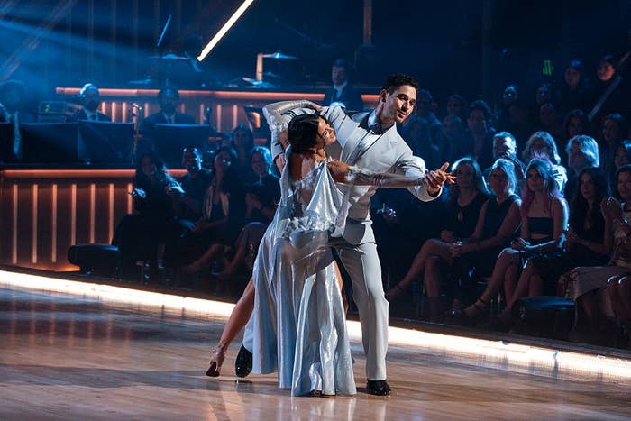 Two dancers gracefully performing connected  a stage, 1  successful  an elegant gown and the different   successful  a crisp  suit, with an assemblage  watching