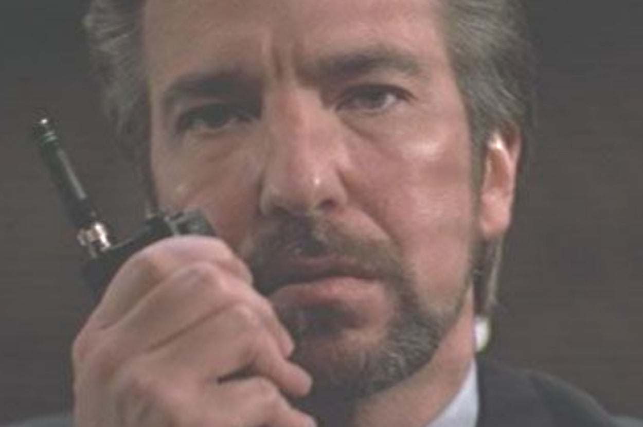 Person holding a walkie-talkie, looking serious, likely from a movie scene