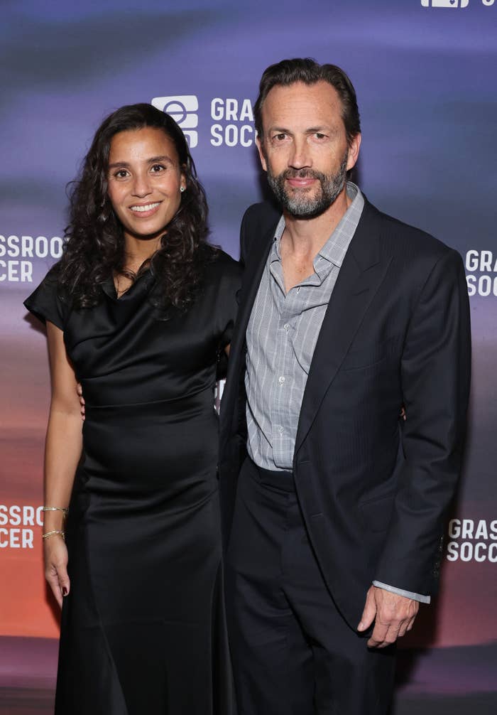 Two individuals posing astatine  a Grassroot Soccer event; 1  successful  a sleek achromatic  dress, the different   successful  a crisp  suit, smiling for the camera