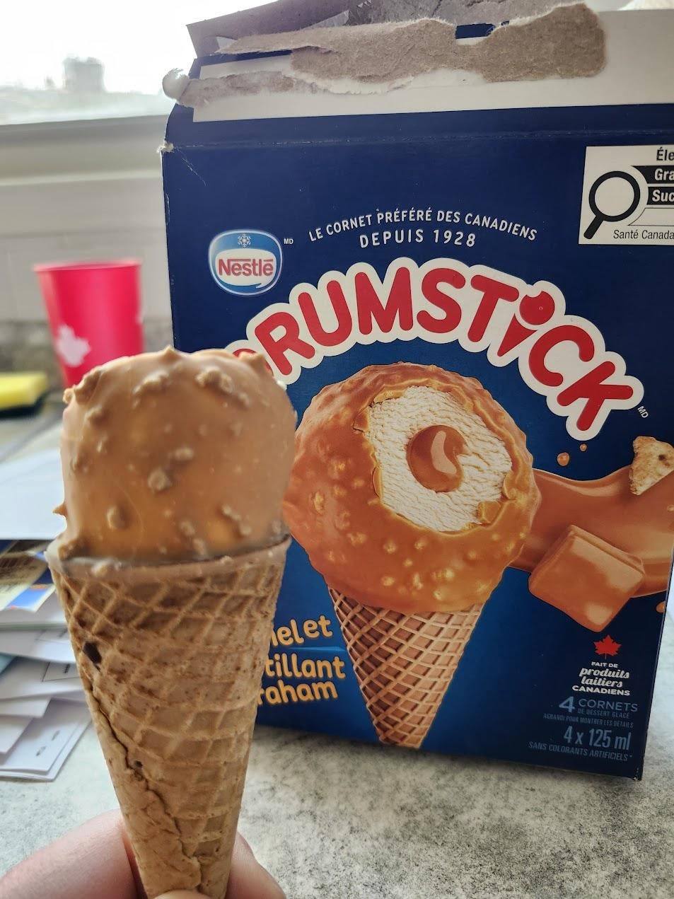 Ice pick  cone held successful  beforehand   of a Drumstick container  with the aforesaid  spirit  shown. Box says “Caramel Brilliant Graham.”