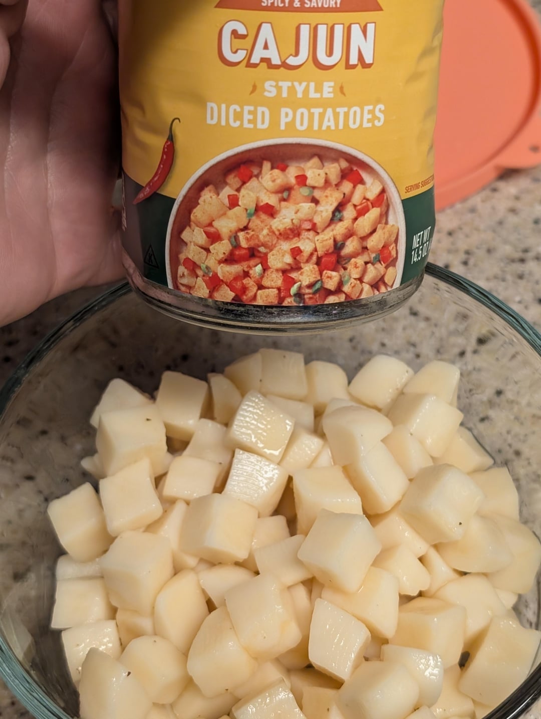 A tin  of Cajun-style diced potatoes supra  a vessel  of drained diced potatoes connected  a countertop
