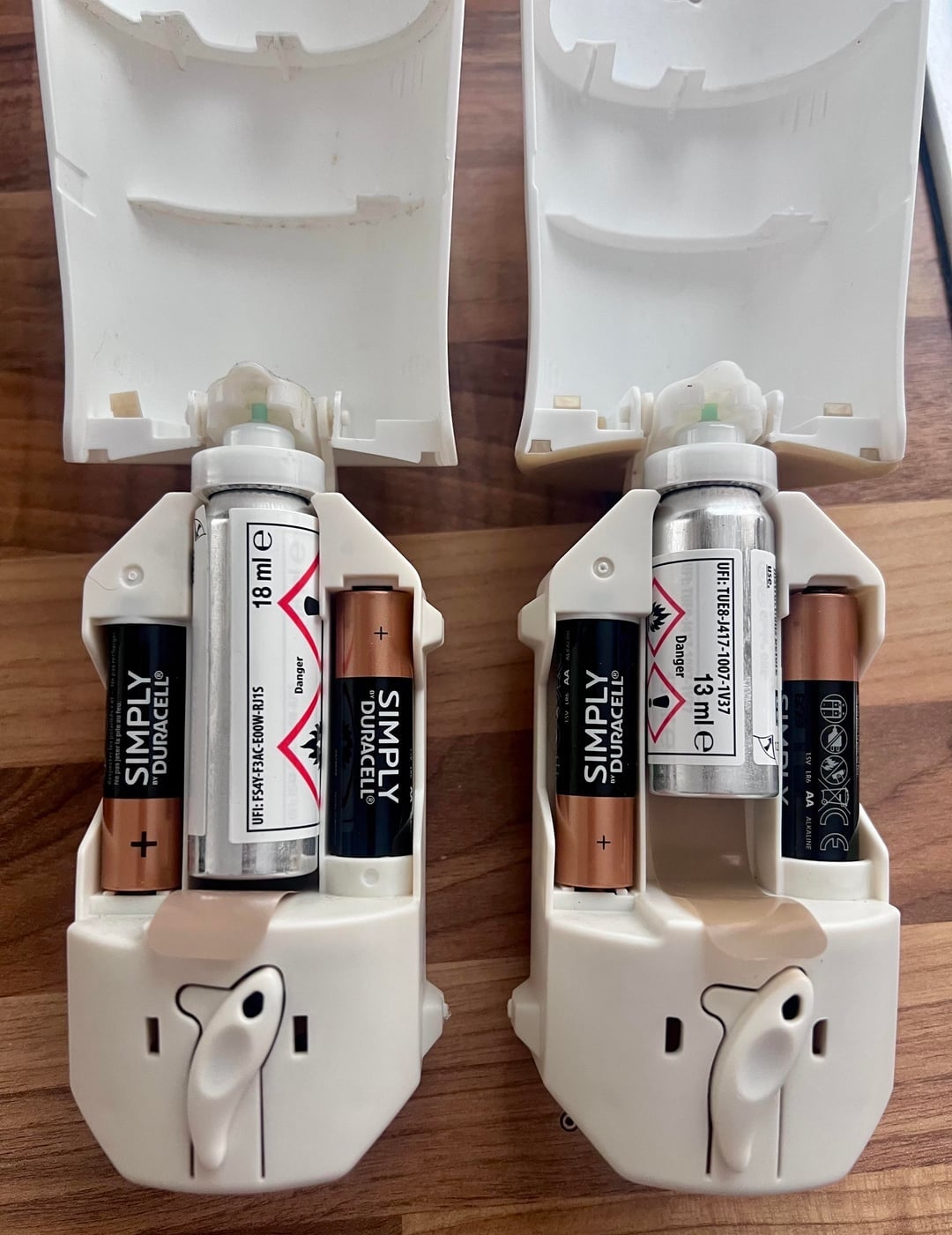 Two unfastened  artillery  compartments of physics  devices, each   containing assorted  brands and sizes of batteries