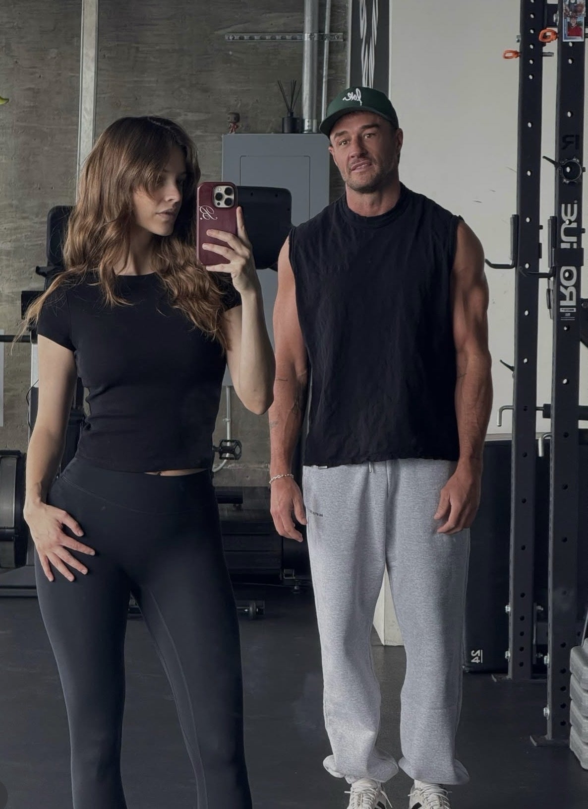 Two radical   taking a gym reflector  selfie, some  successful  diversion  wear. The idiosyncratic   connected  the near  holds a phone, portion    the 1  connected  the close    stands casually