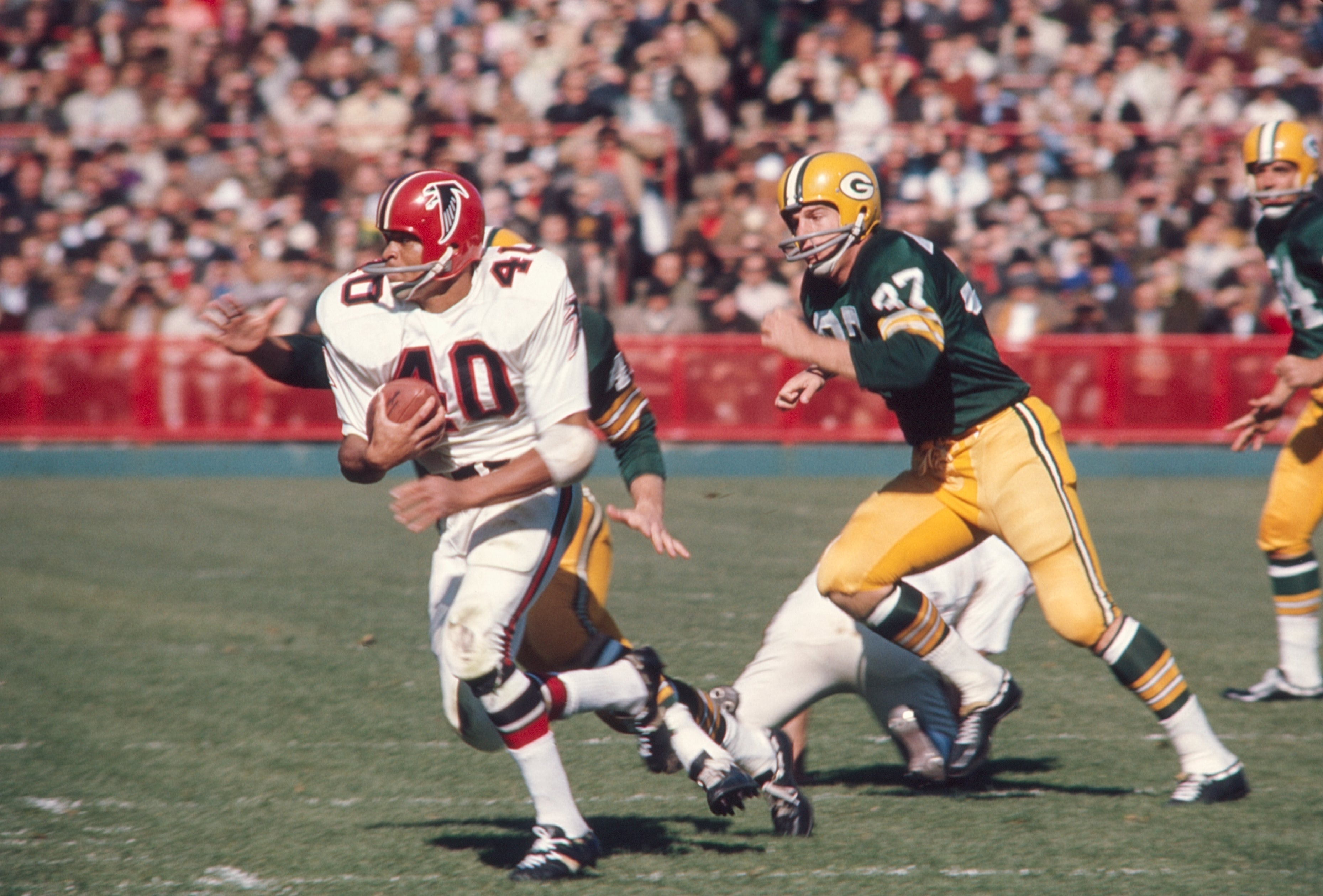 Football player runs with the ball during a game, pursued by opponents