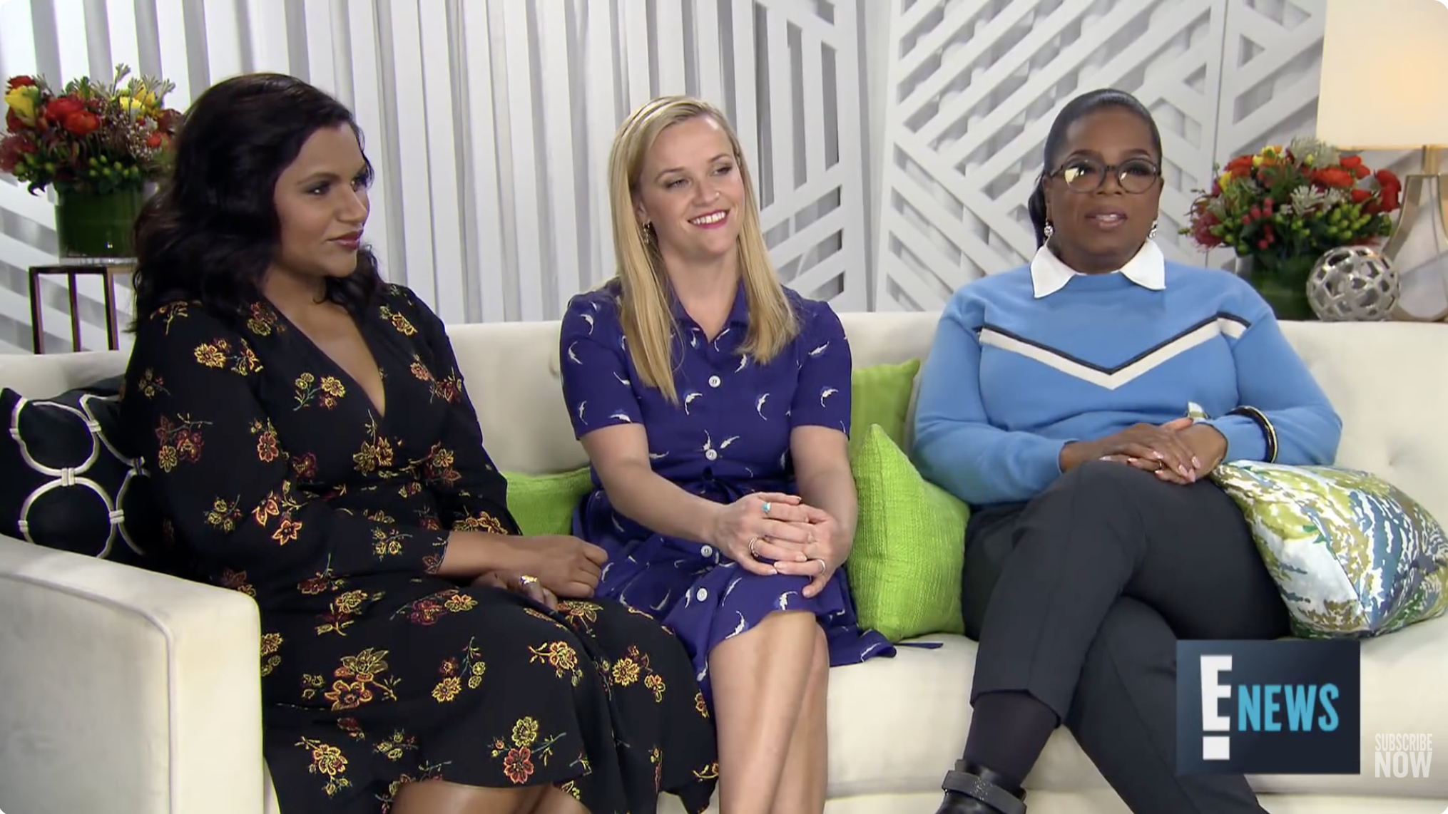Three women sit on a couch during a panel interview. The one on the left wears a floral dress, the middle wears a blue dress, and the right wears a blue sweater