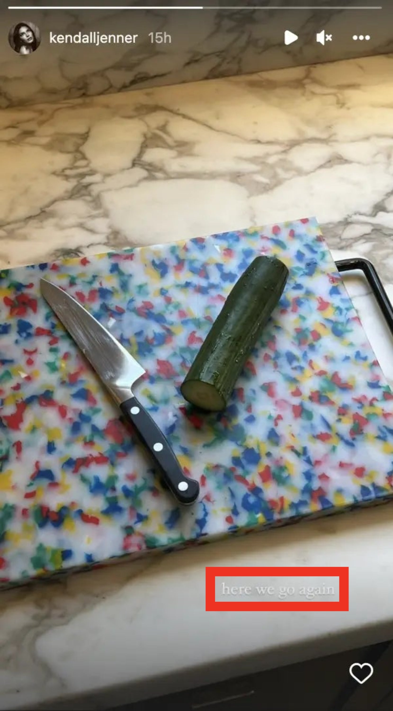 Cut cucumber next to a kitchen knife on a colorful cutting board. Text overlay reads, "here we go again."
