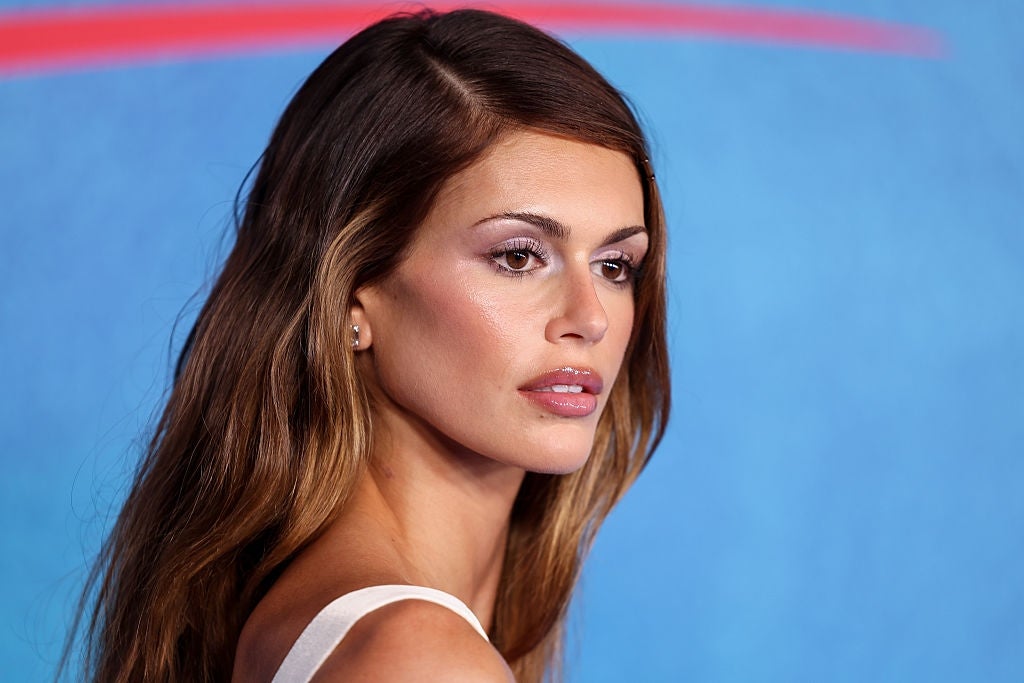 Person posing elegantly, wearing a sleeveless top with a sleek hairstyle, at a celebrity event