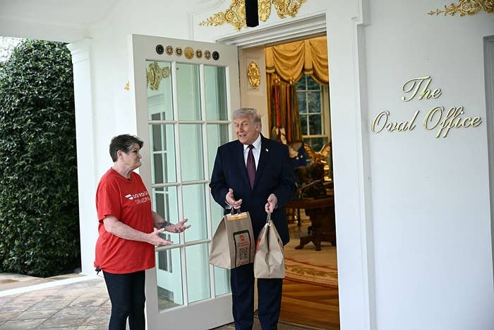 Person successful  casual apparel  talks with a suited antheral   holding takeaway bags astatine  the entranceway  of the Oval Office