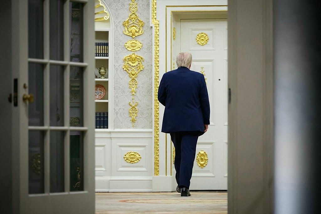 A idiosyncratic   successful  a suit   walks distant  wrong  an ornate country   with intricate golden  details and shelves filled with books