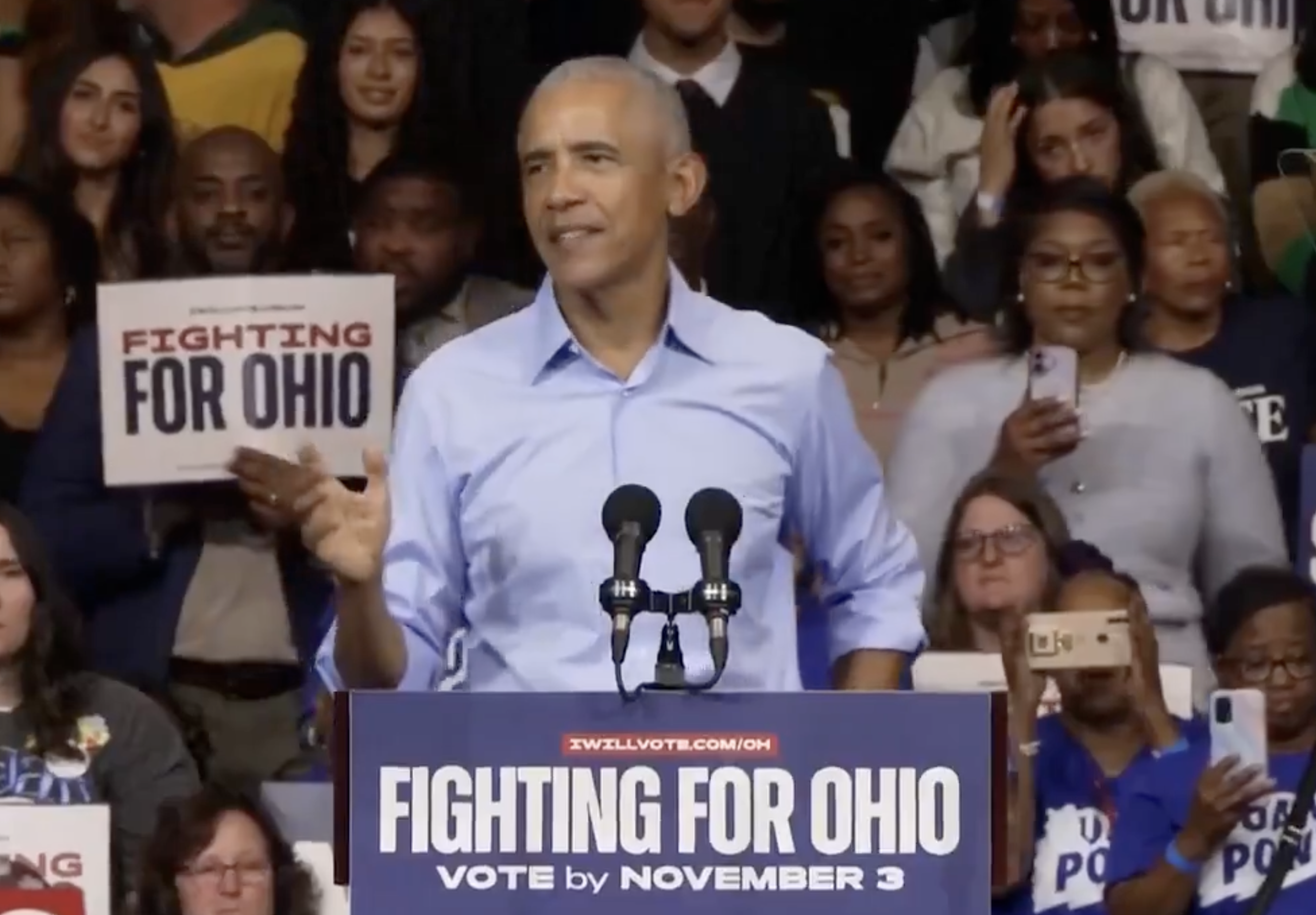 A idiosyncratic   is speaking astatine  a "Fighting for Ohio" event, surrounded by supporters holding signs