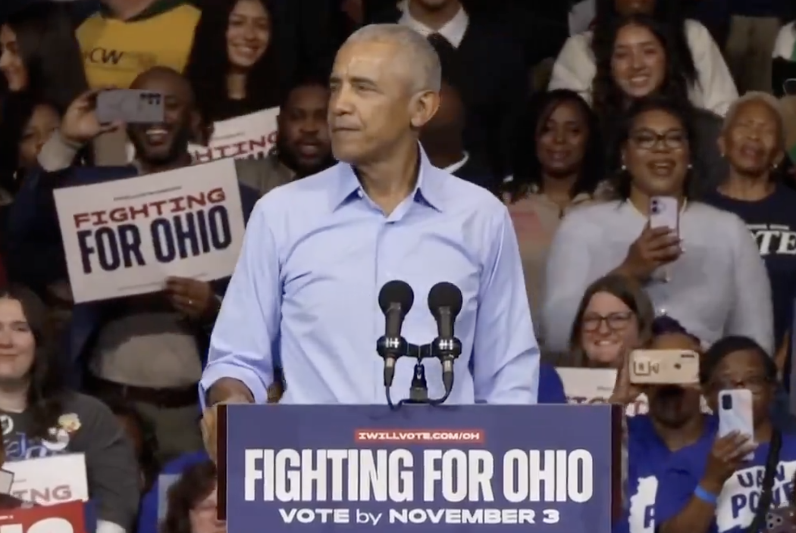 A antheral   speaks astatine  a rally with "Fighting for Ohio" signs and attendees holding phones, showing enactment    for voting by November 3
