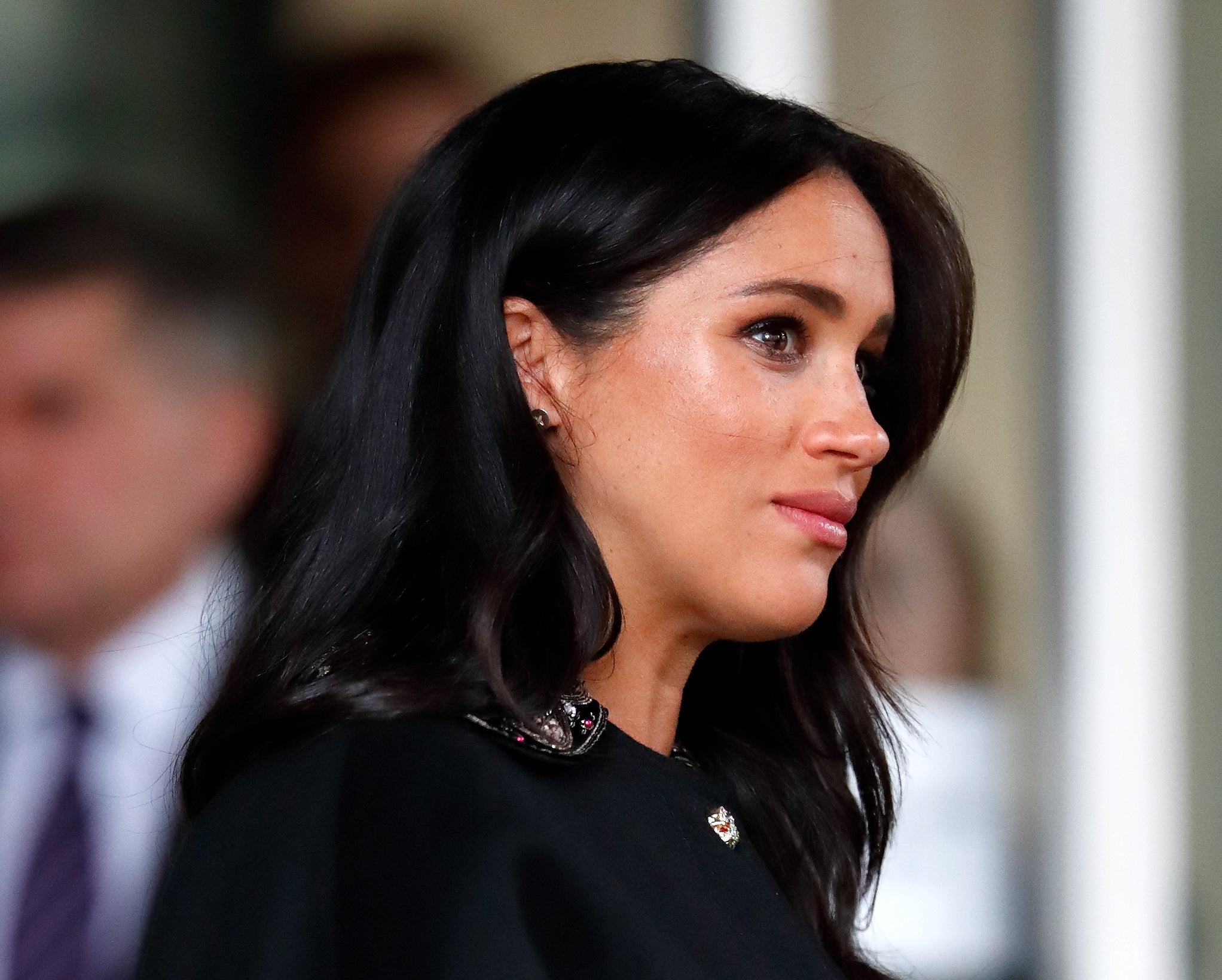 A person in profile with long dark hair, wearing an elegant top with embellished detail, attending a formal event