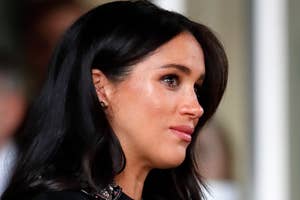 A person in profile with long dark hair, wearing an elegant top with embellished detail, attending a formal event