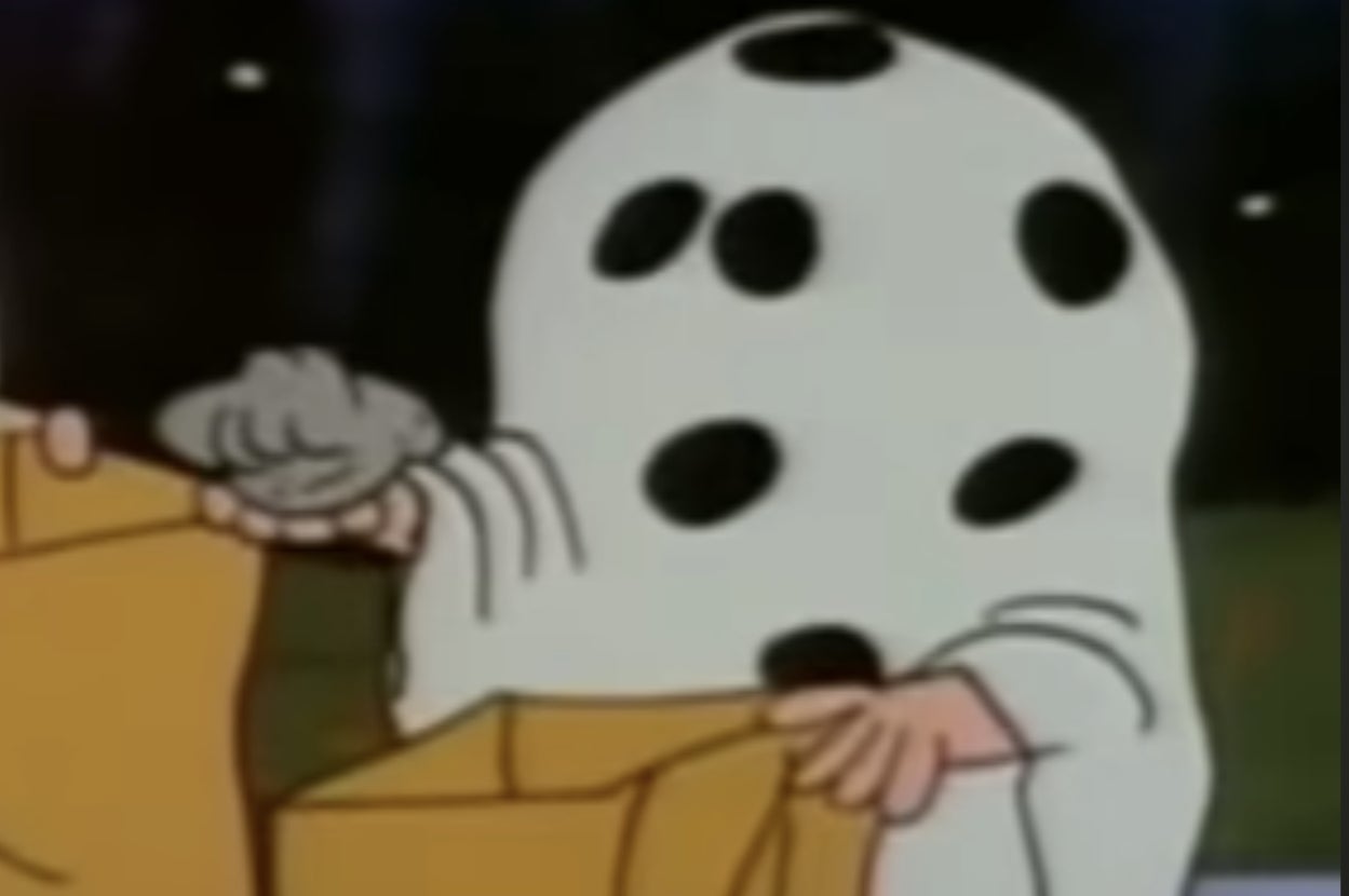 Cartoon character in a white sheet with black spots holds a bag open, resembling a ghost costume at Halloween