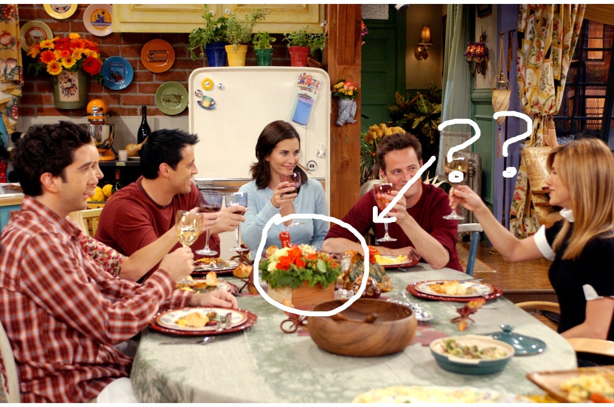 Five people sit around a table, toasting with wine glasses in a cozy, colorful kitchen