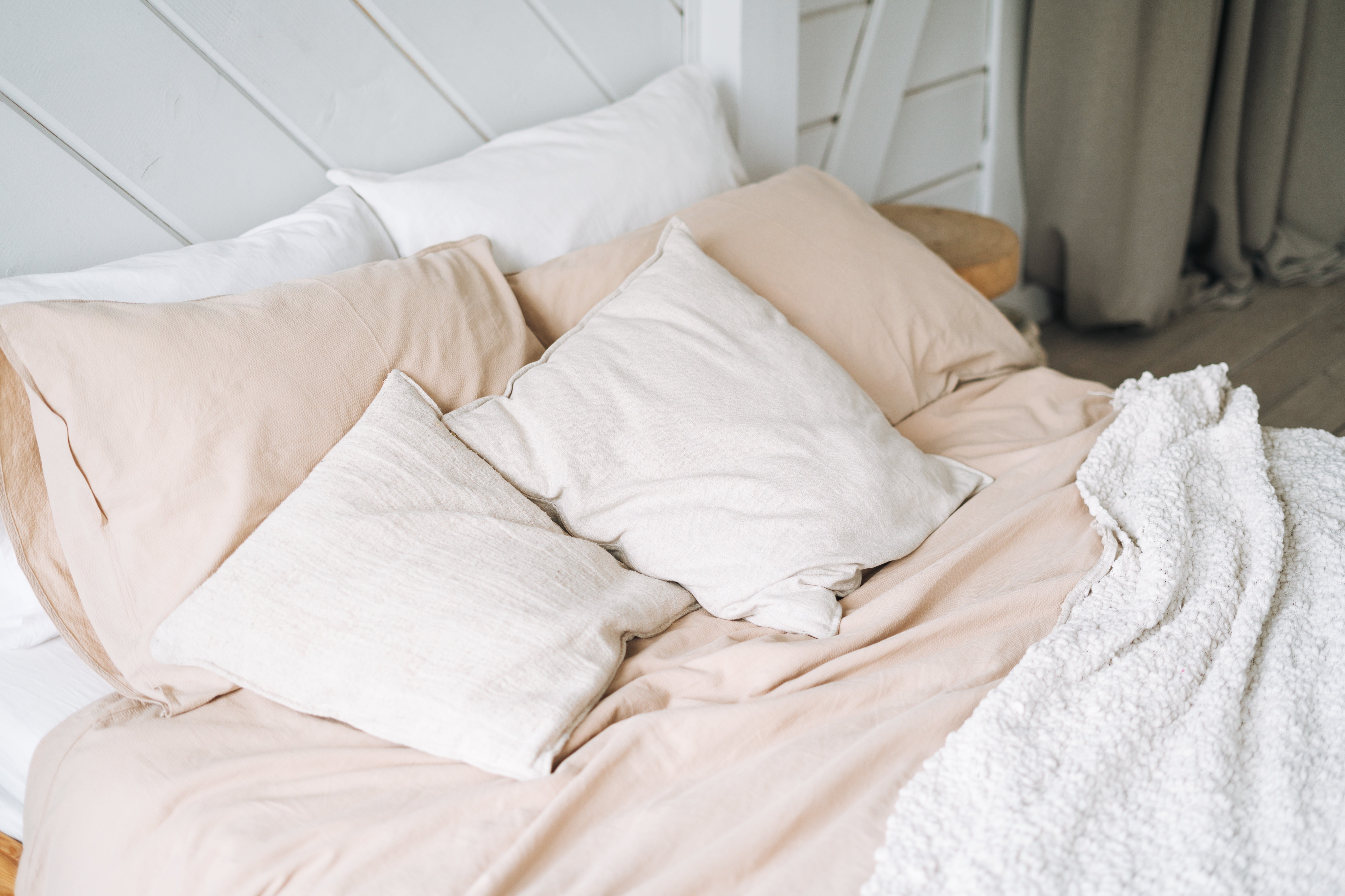 Unmade bed with neutral-toned pillows and blanket, creating a cozy and inviting atmosphere