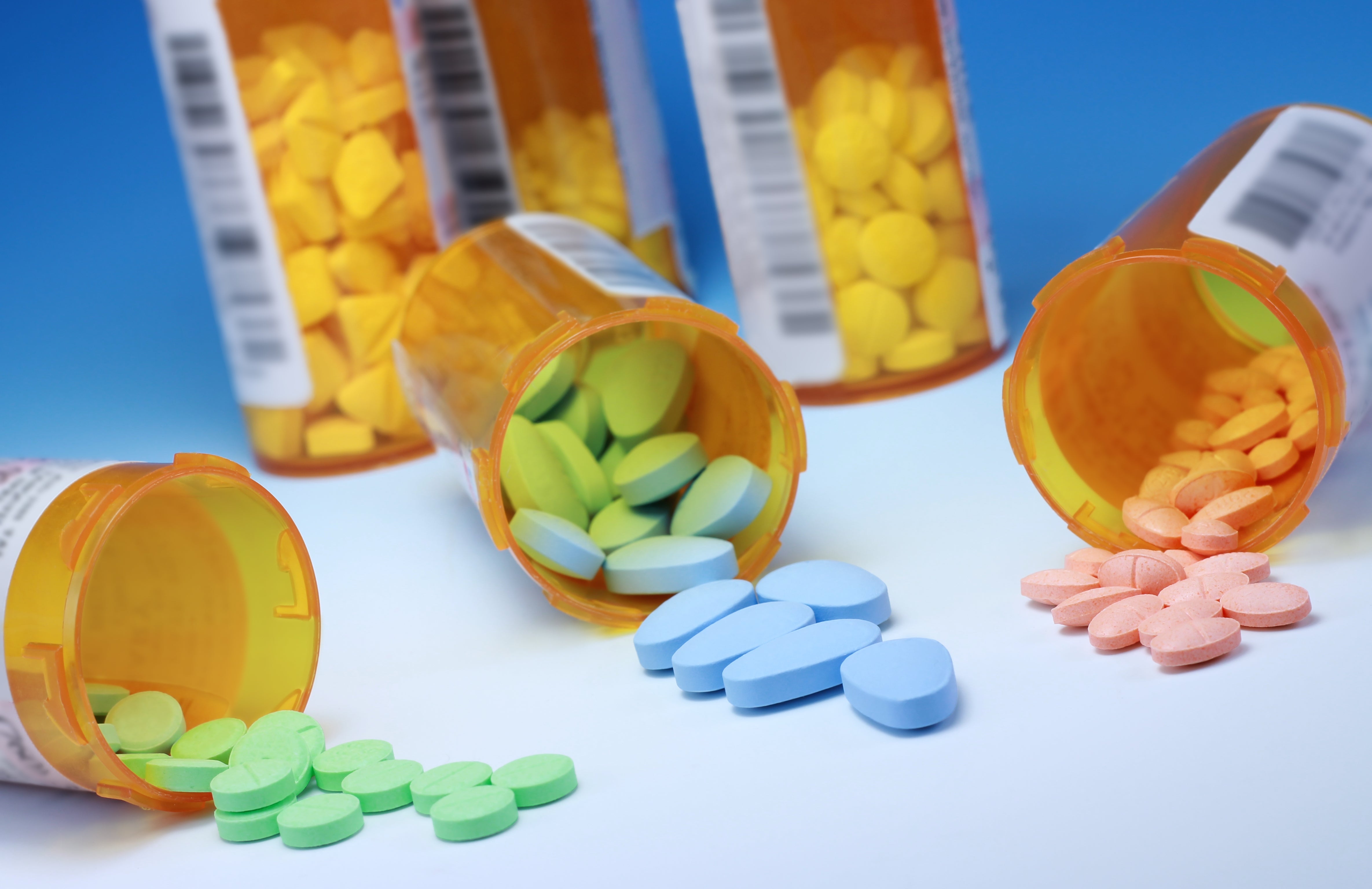 Prescription bottles tipped over, spilling colorful tablets and pills onto a surface