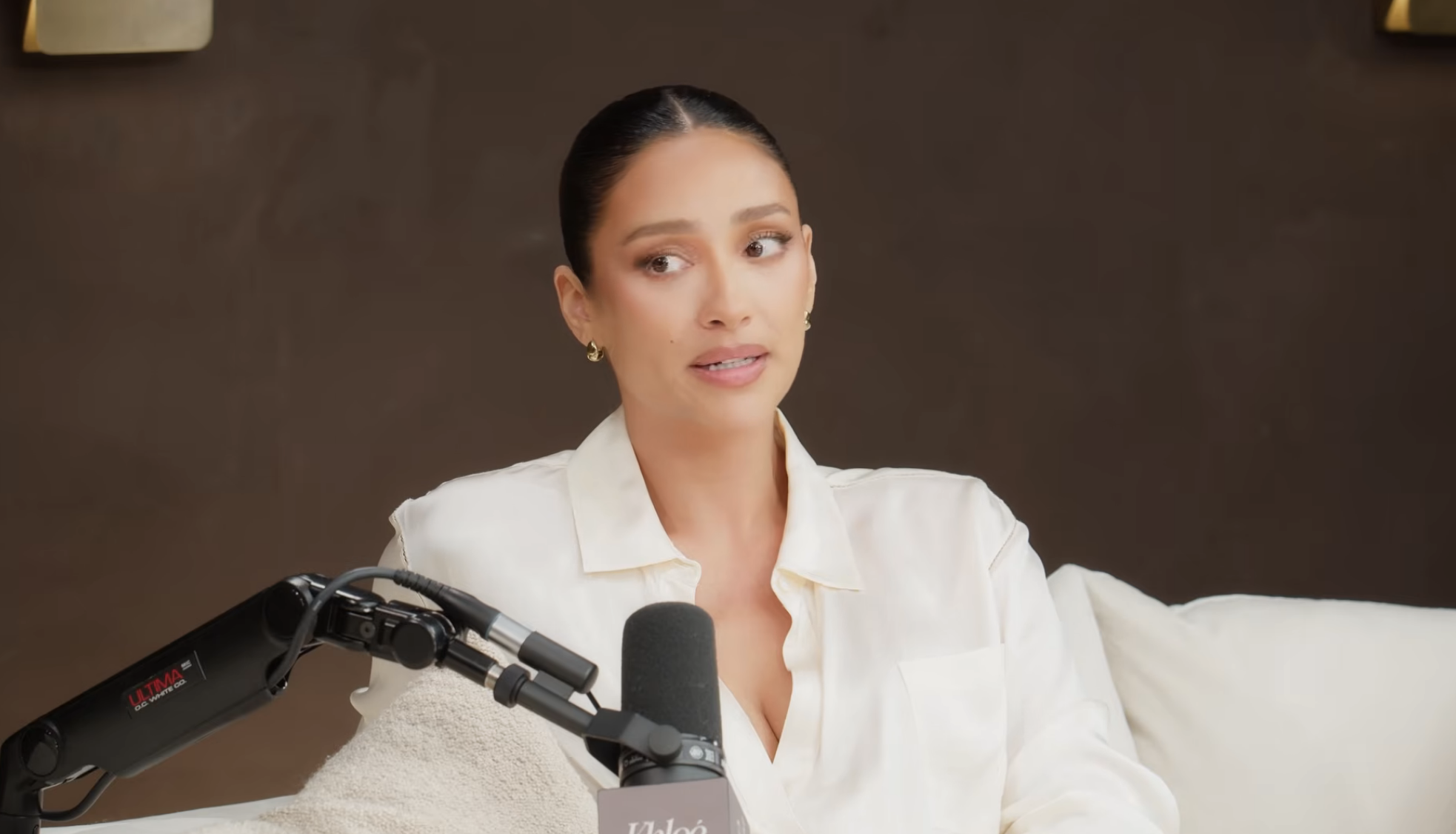 Person in a white blouse speaking into a microphone during a podcast interview