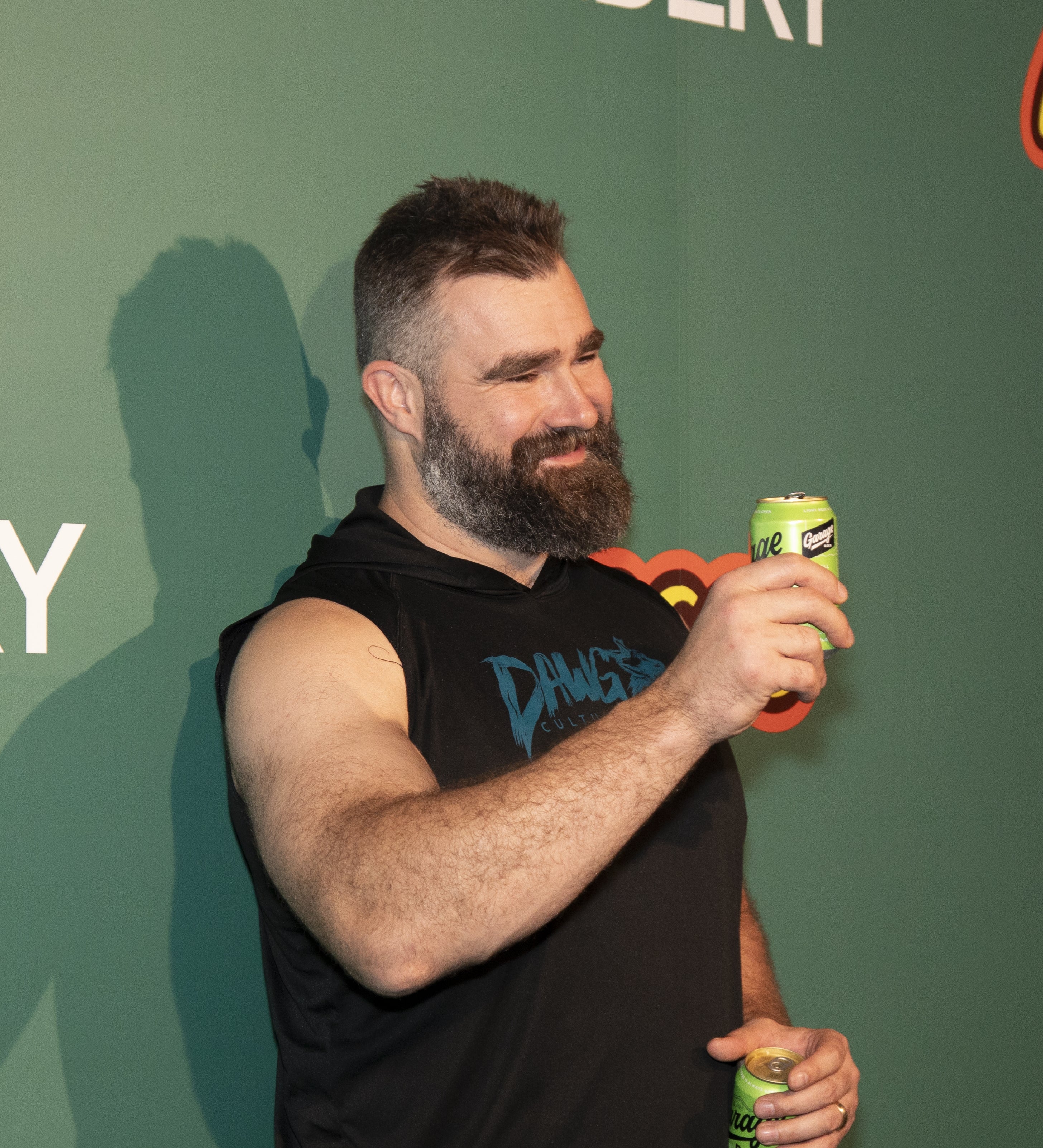Jason holding a drink can, wearing a sleeveless hoodie