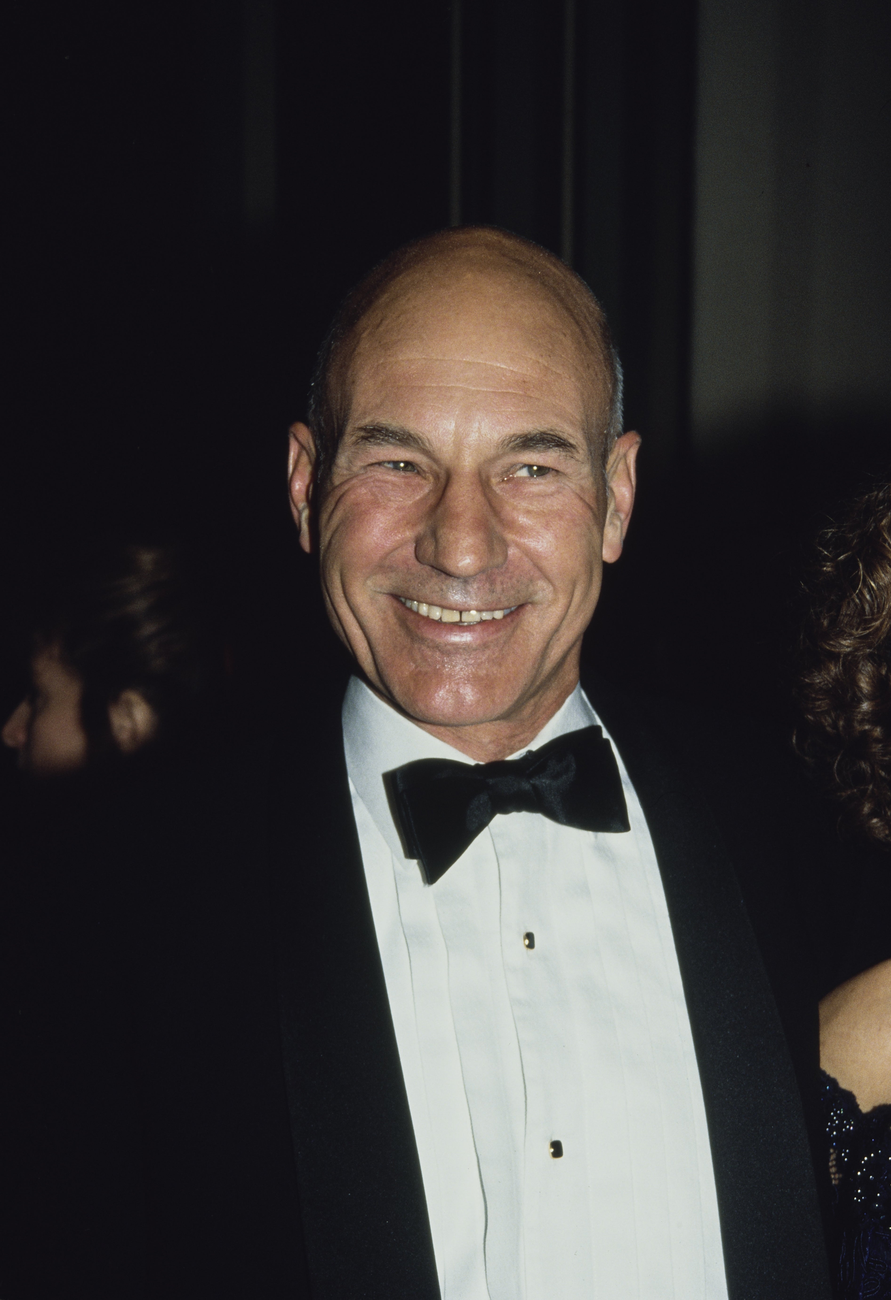 Person in formal attire with a bow tie, smiling at an event