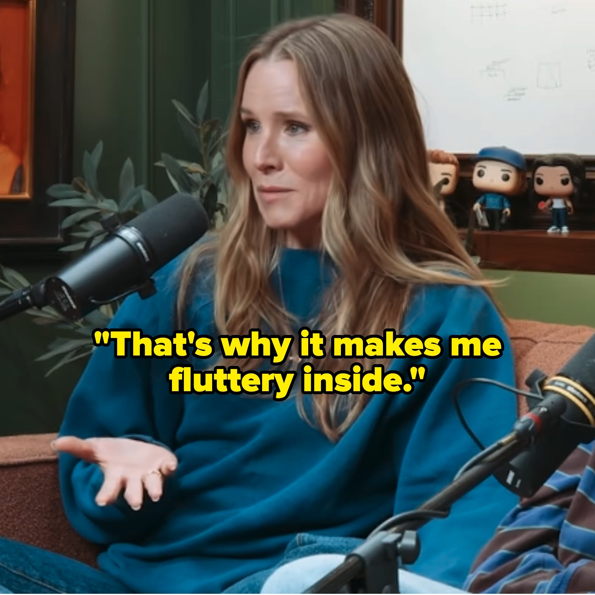 Kristen Bell in a casual blue sweater speaking into a microphone in a recording studio