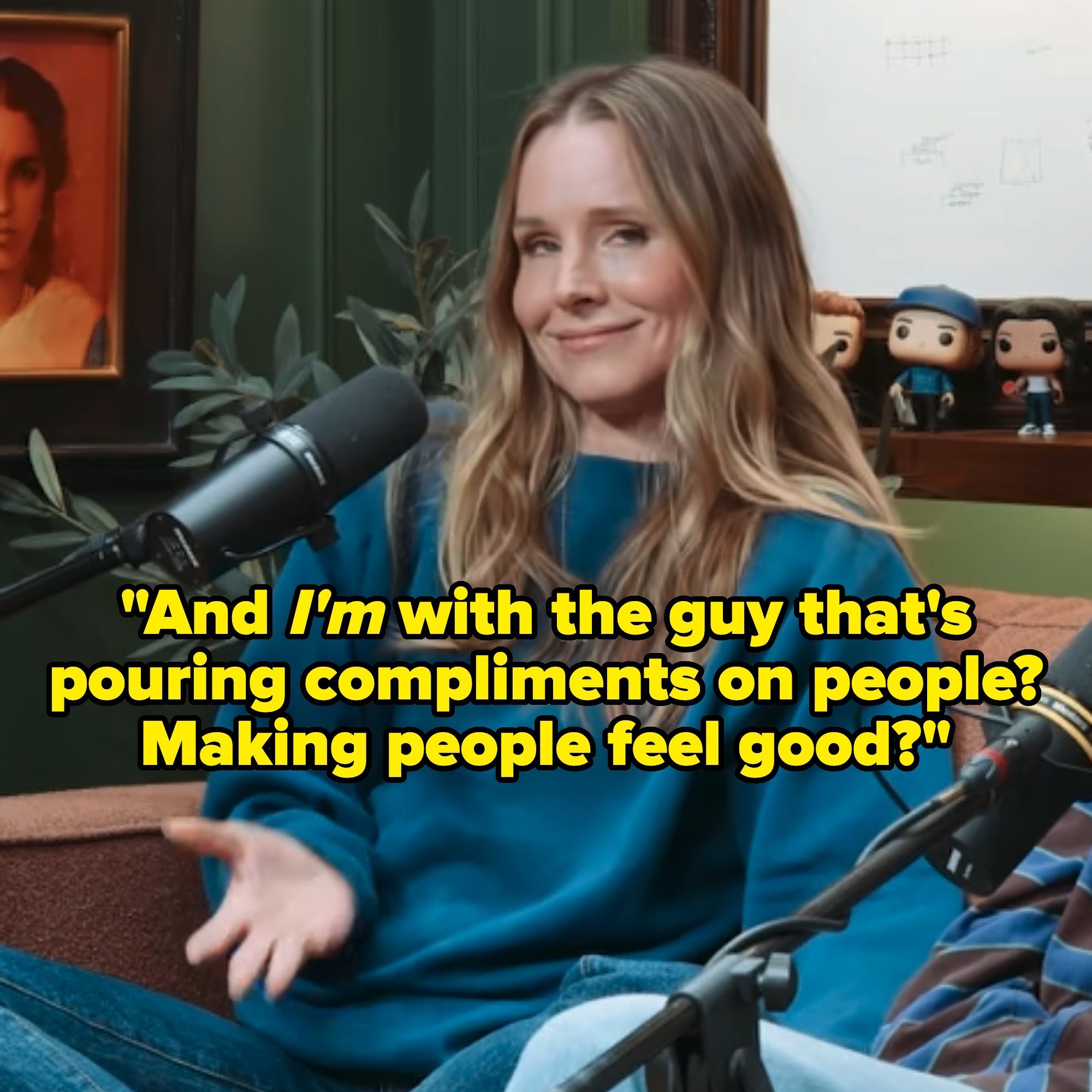 Kristen Bell in a casual blue sweater speaking into a microphone in a recording studio