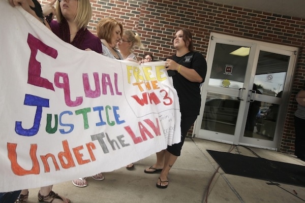 Women hold a sign at the Craighead County Court House in Jonesboro, Ark., Friday, Aug. 19, 2011, ...