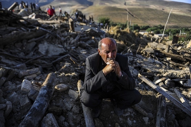 A victim of Saturday's earthquake sits on the ruins of buildings at the village of Bajebaj near the city of Varzaqan in northwestern Iran, Sunday, Aug. 12, 2012. Twin earthquakes in Iran have killed at least 250 people and injured over 2,000, Iranian state television said on Sunday, after thousands spent the night outdoors after their villages were leveled and homes damaged in the country's northwest. Iran is located on seismic fault lines and is prone to earthquakes. It experiences at least one earthquake every day on average, although the vast majority are so small they go unnoticed.