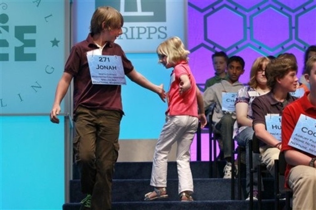 Jonah Gunter, 13, of Leavenworth, Wash., left, high-fives Lori Anne Madison, 6, of Woodbridge, Va., the youngest speller in at the National Spelling Bee, after she spelled her word correctly, Wednesday, May 30, 2012, during the National Spelling Bee in Oxon Hill, Md.