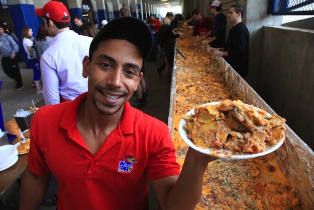 Eddie Diaz holds one of the hundreds of plates of nachos that came from a Guinness Book record 80-foot tray of chips, cheese and beef topped of with pica de gallo at the Kansas Relays, Saturday, April 21, 2012, in Lawrence, Kansas. Attendees paid a donation of $1.00 or a canned food item for their servings, with proceeds going to the Lawrence Interdenominational Nutrition Kitchen.