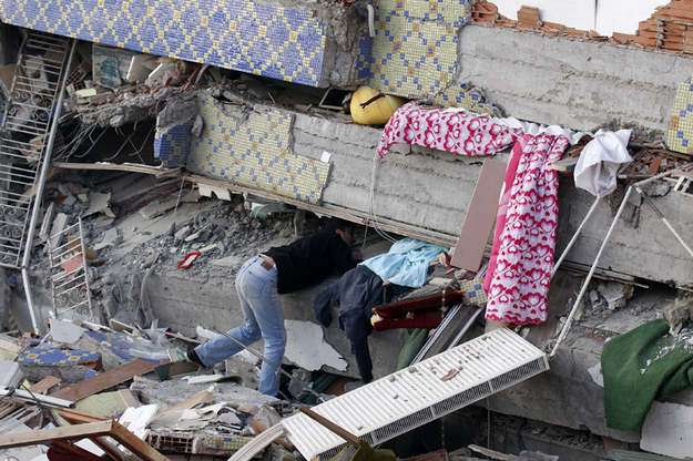 A man searches for his relatives under a collapsed building after an earthquake in Ercis.