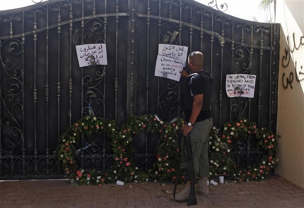 September 18, 2012. A Libyan government militia guarding the main entrance of the U.S. consulate that was attacked last week, fixes a note written by Libyans against the attack, in Benghazi city.