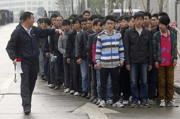 An employee directs job seekers to queue up outside the Foxconn recruitment center in Shenzhen, Guangdong province February 22, 2012.