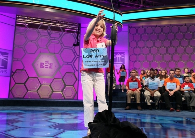 NATIONAL HARBOR, MD- MAY 30: Six-year-old Lori Anne Madison reaches for the microphone before mispelling the word 'ingluvies' during the third round of the 2012 Scripps National Spelling Bee competition May 30, 2012 in National Harbor, Maryland. Lori who is the youngest speller to participate failed to make it to the finals of the annual competition. 278 spellers are competing in the 85th annual competition.