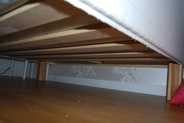Beautiful wall paper can be seen from under the bed.