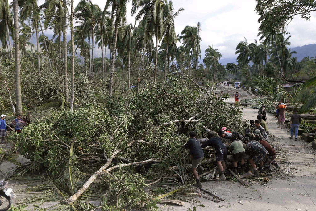 Filipino soldiers and residents work to remove a fallen tree from a road in New Bataan township, Compostela Valley in southern Philippines, Dec. 5, 2012, a day after Typhoon Bopha made landfall.